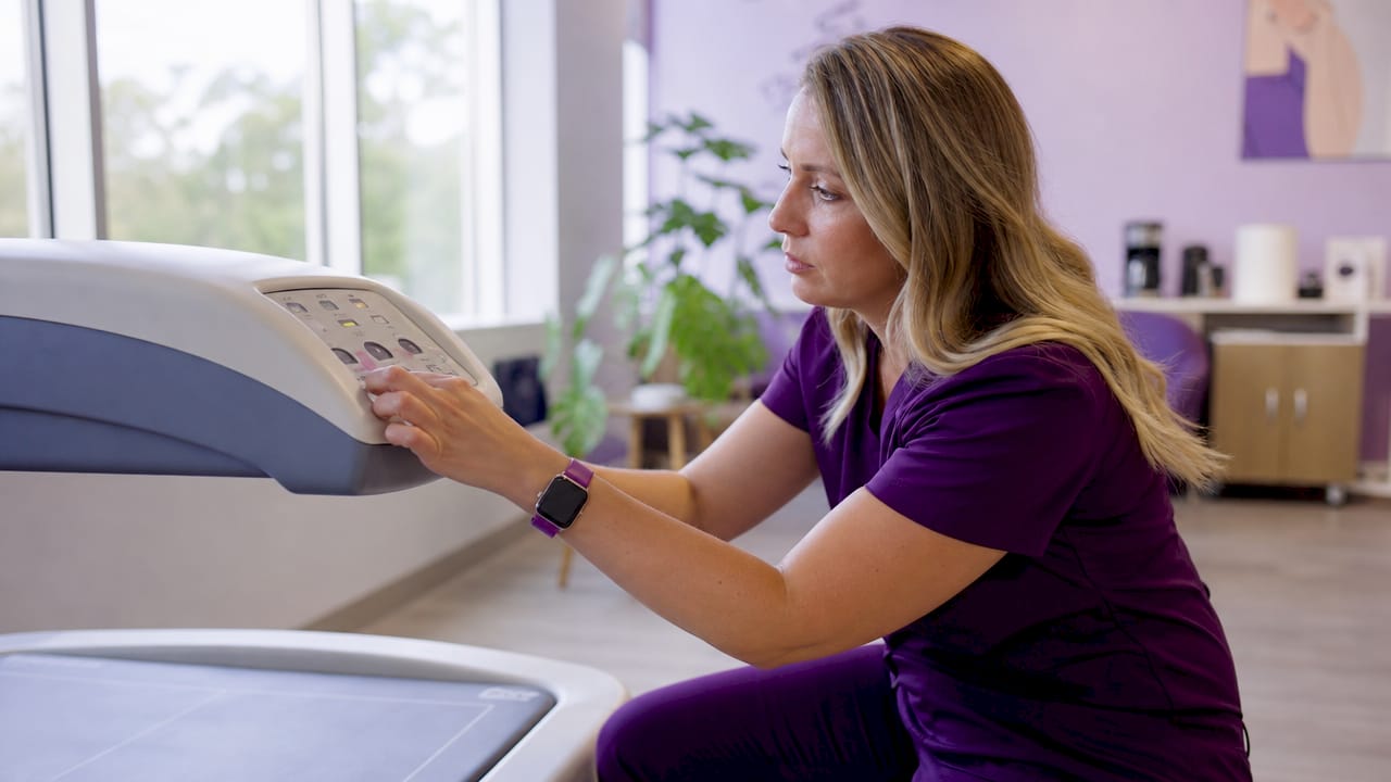 Technician adjusting DXA scan machine in hospital room