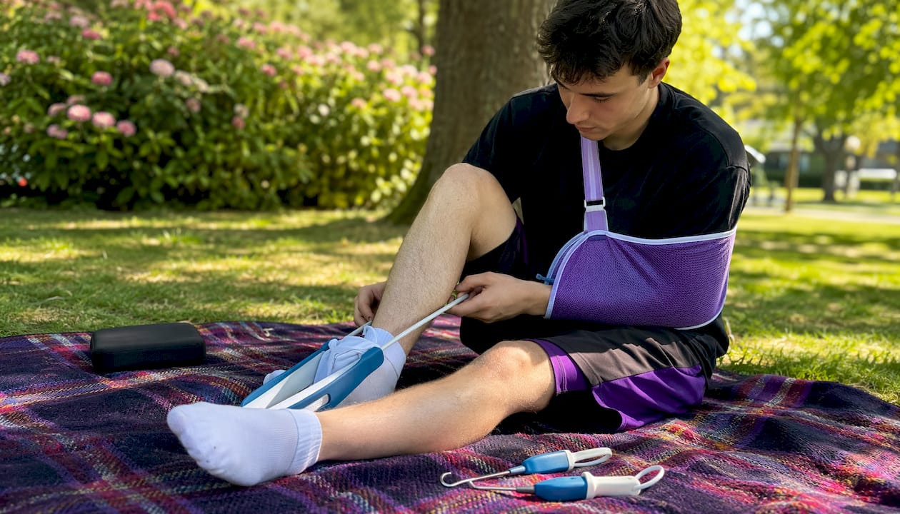 Man using adaptive dressing tools sitting on chair