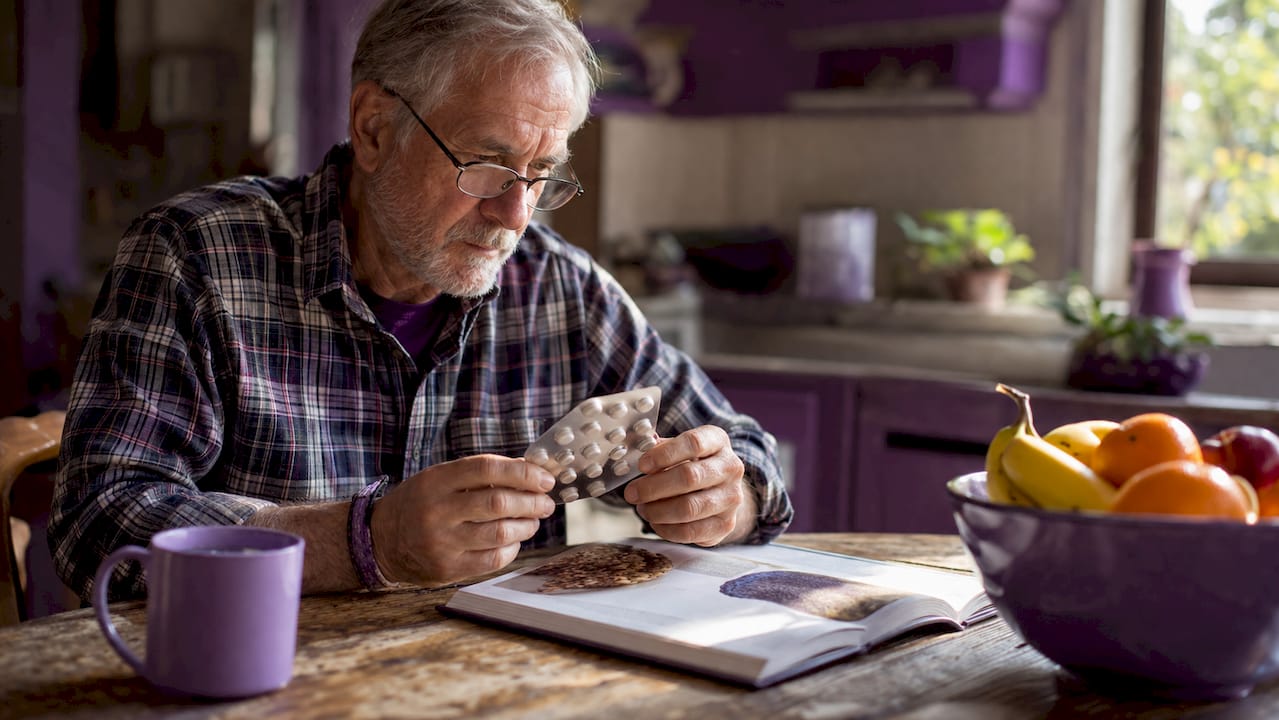 Man examining calcium supplements in home office