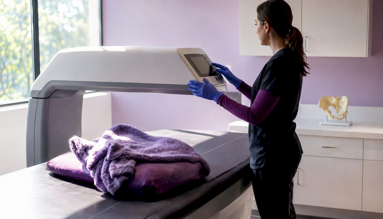 Technician adjusting DXA scanner controls
