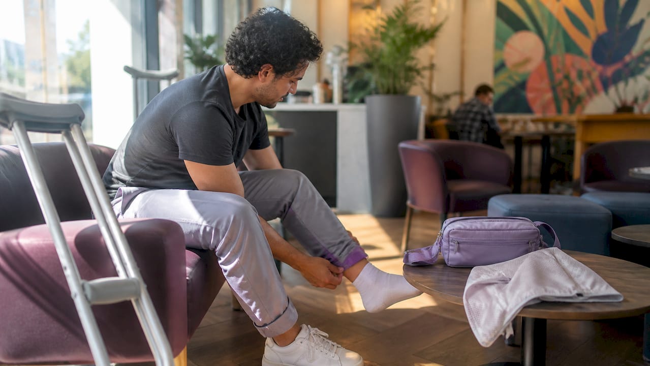 Person pulling up adaptive recovery pants while seated