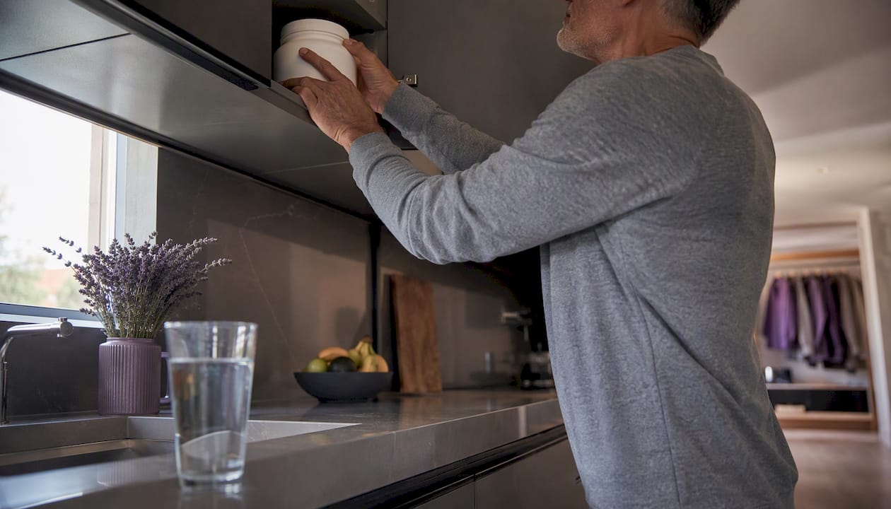 Hands opening collagen supplement jar in kitchen