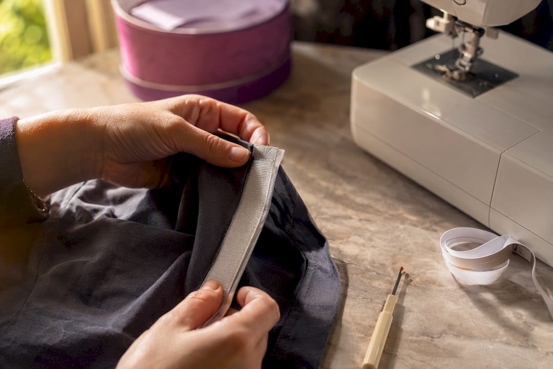 Hands modifying clothing with sewing tools