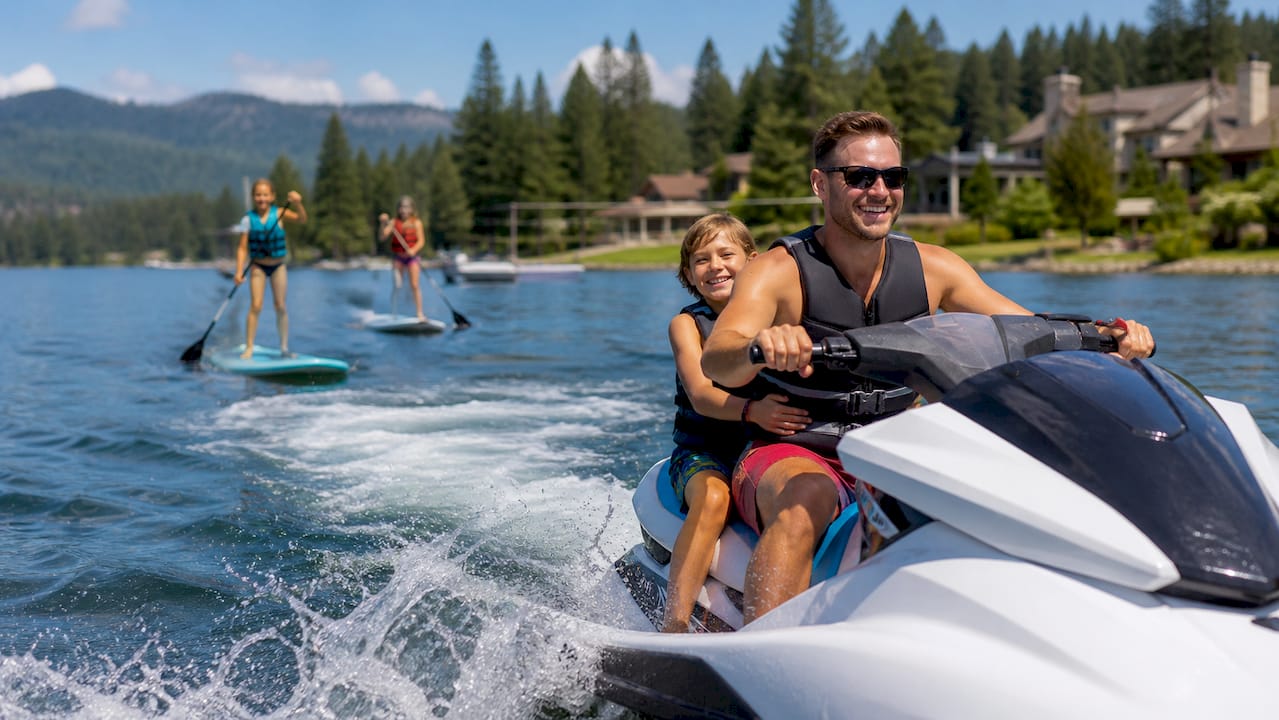 Families on jet skis and paddleboards at calm lake