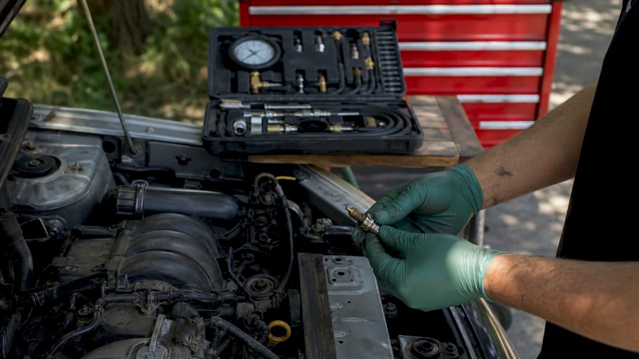 Hands removing spark plug for compression test