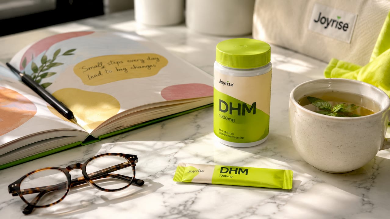 Flat lay of Joyrise DHM capsules with herbal tea and glasses