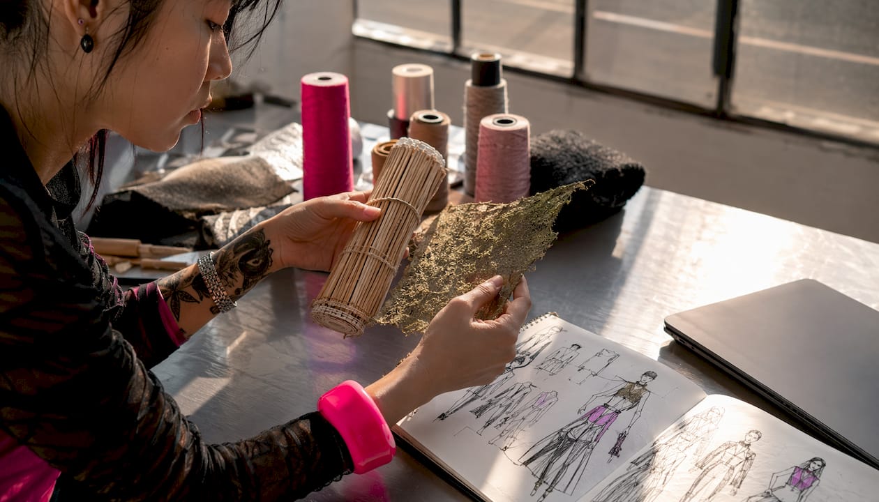 Close-up of designer examining sustainable fabric samples at workspace