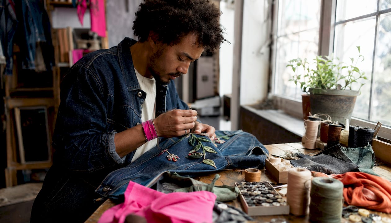 Tailor hand-stitching upcycled denim with eco materials