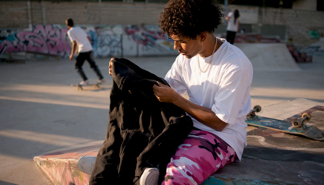 Hands examining skate hoodie stitching close-up