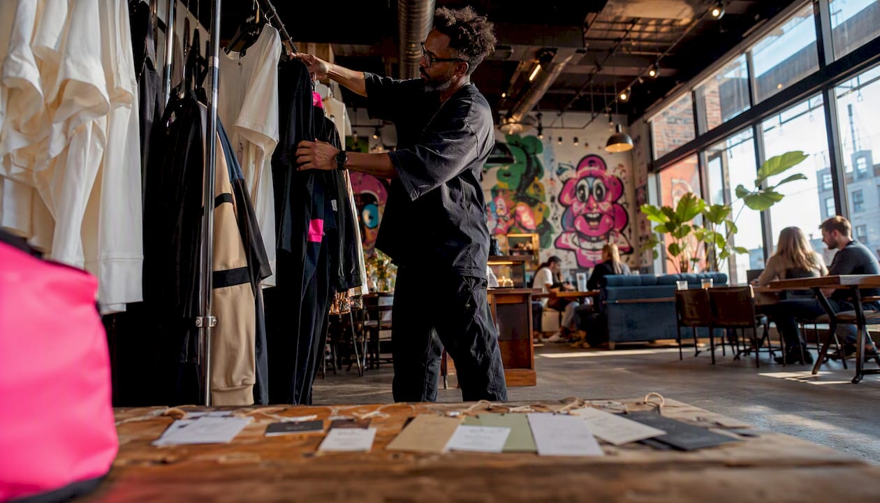 Man arranging sustainable streetwear in boutique