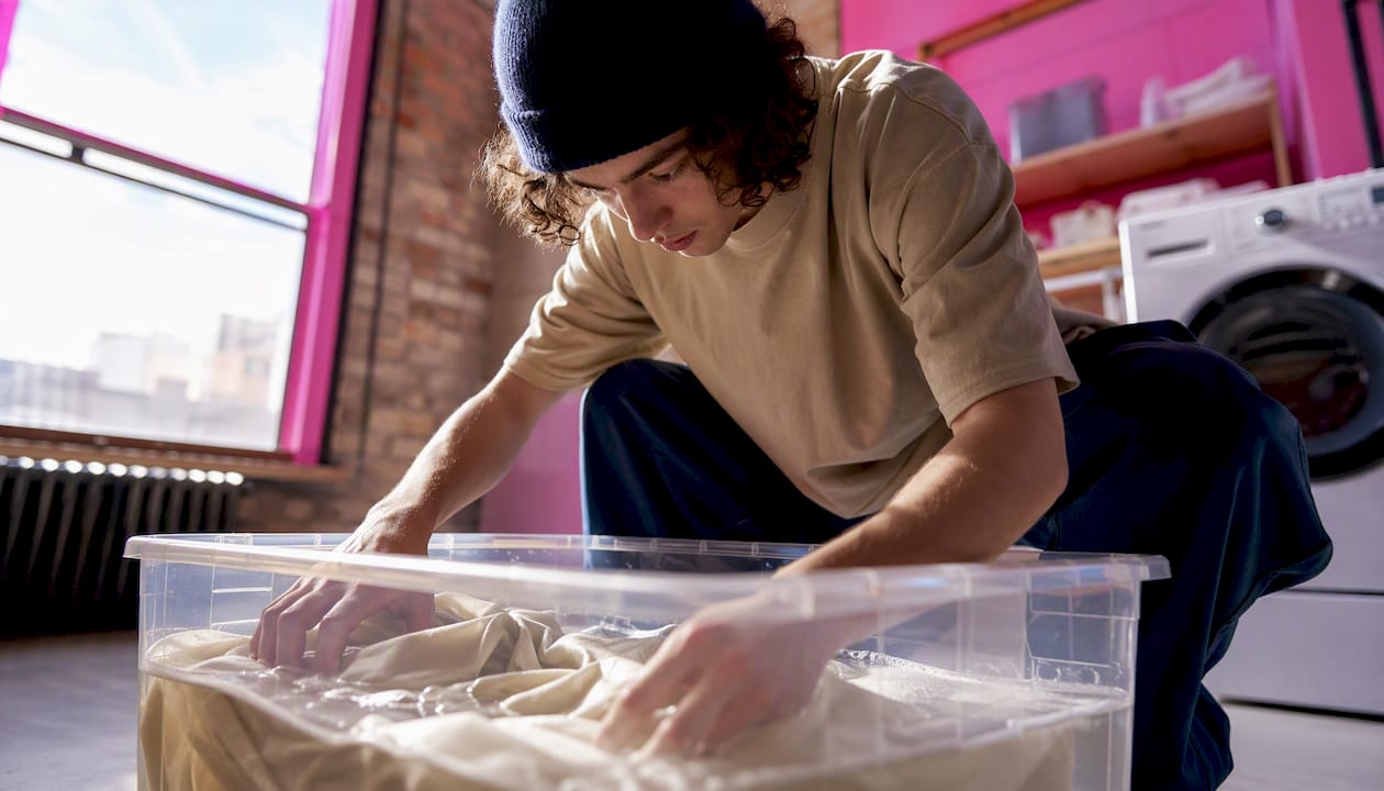 Hands soaking hoodie in baking soda bath