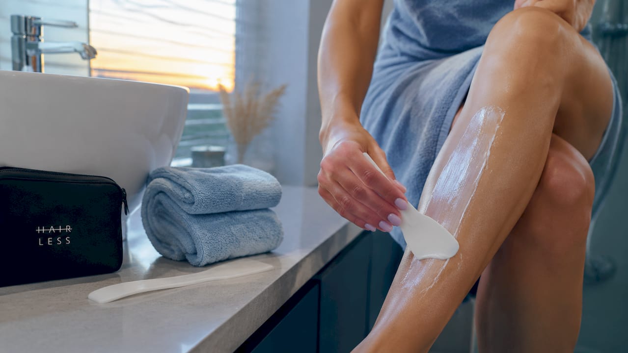 V kozmetickom salóne odborníčka nanáša depilačný krém na predlaktie klientky.