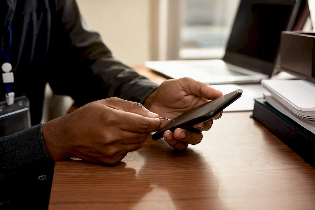 Hands verifying mobile device with SIM tool