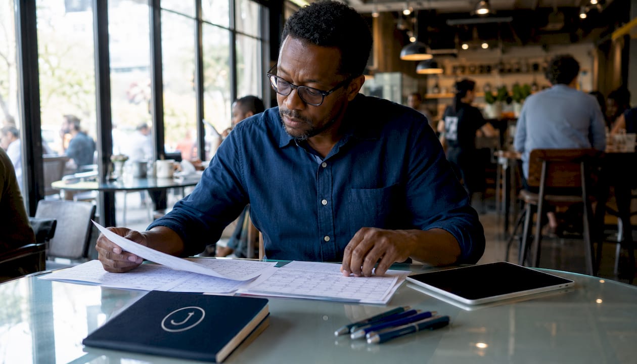 Manager organizing employee availability forms at home