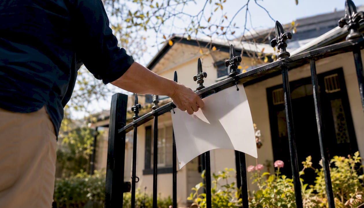 Hand removing vacancy sign from rental property gate