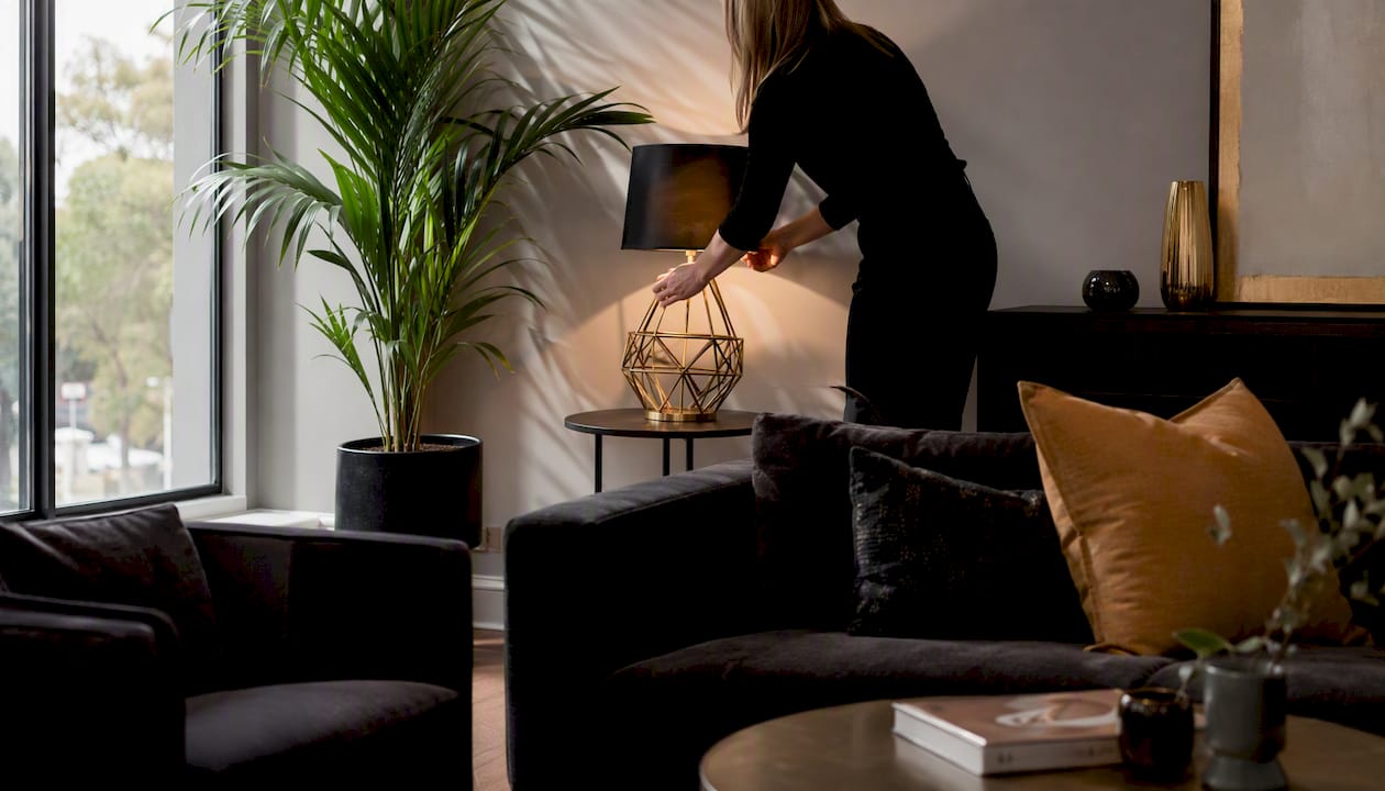 Hands adjusting lamp in premium staged living room