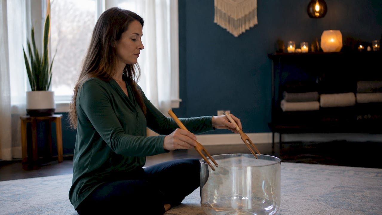 Hands holding tuning forks over water bowl