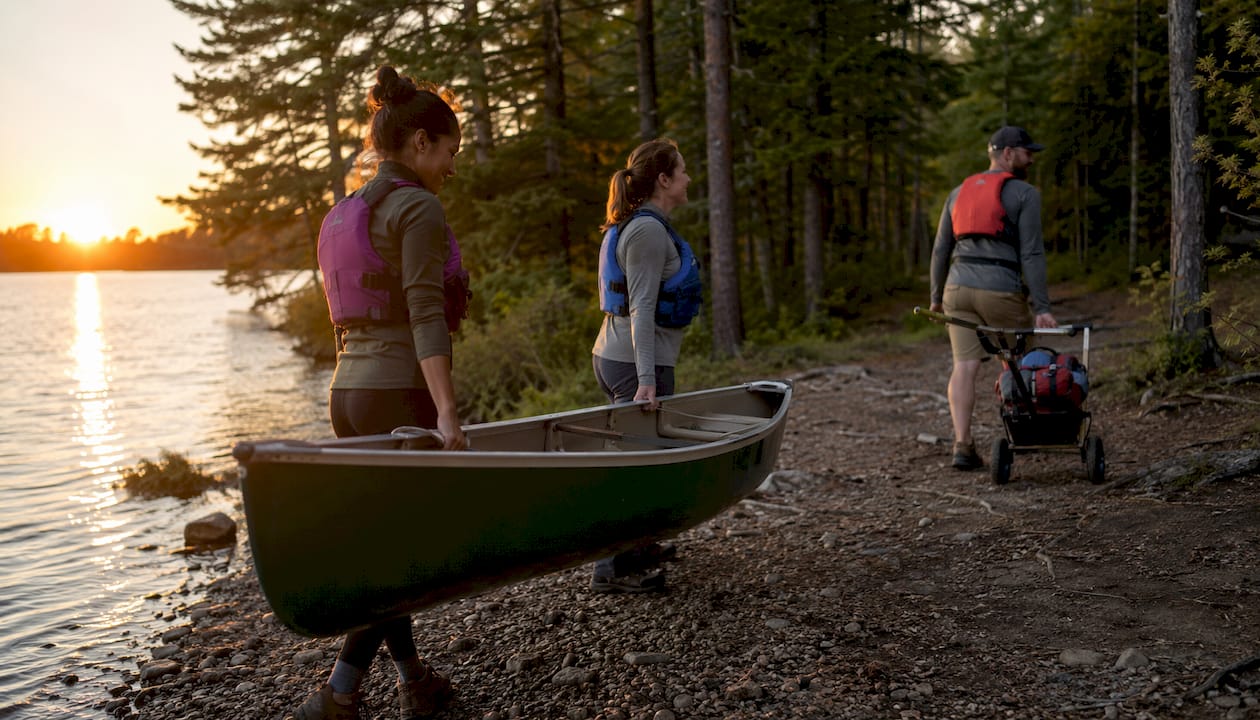 Paddlers unloading canoe on lake shore