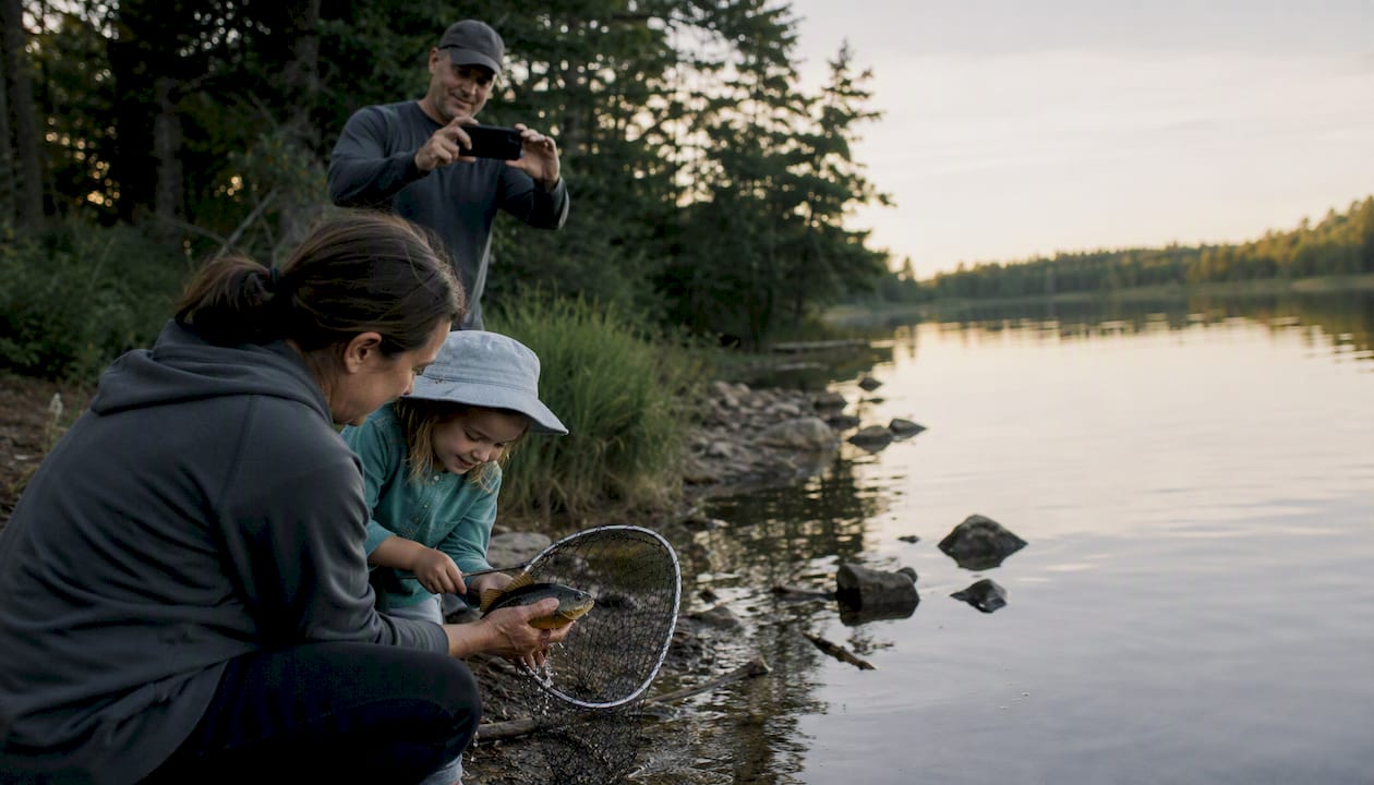 Family releasing fish using net and wet hands
