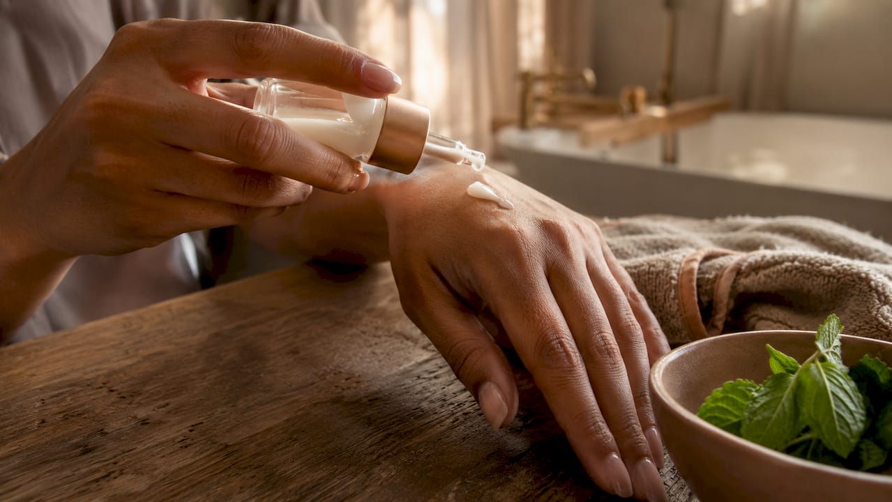 Hands applying serum from dropper bottle