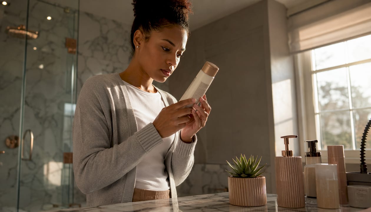 Woman reading shampoo label ingredients