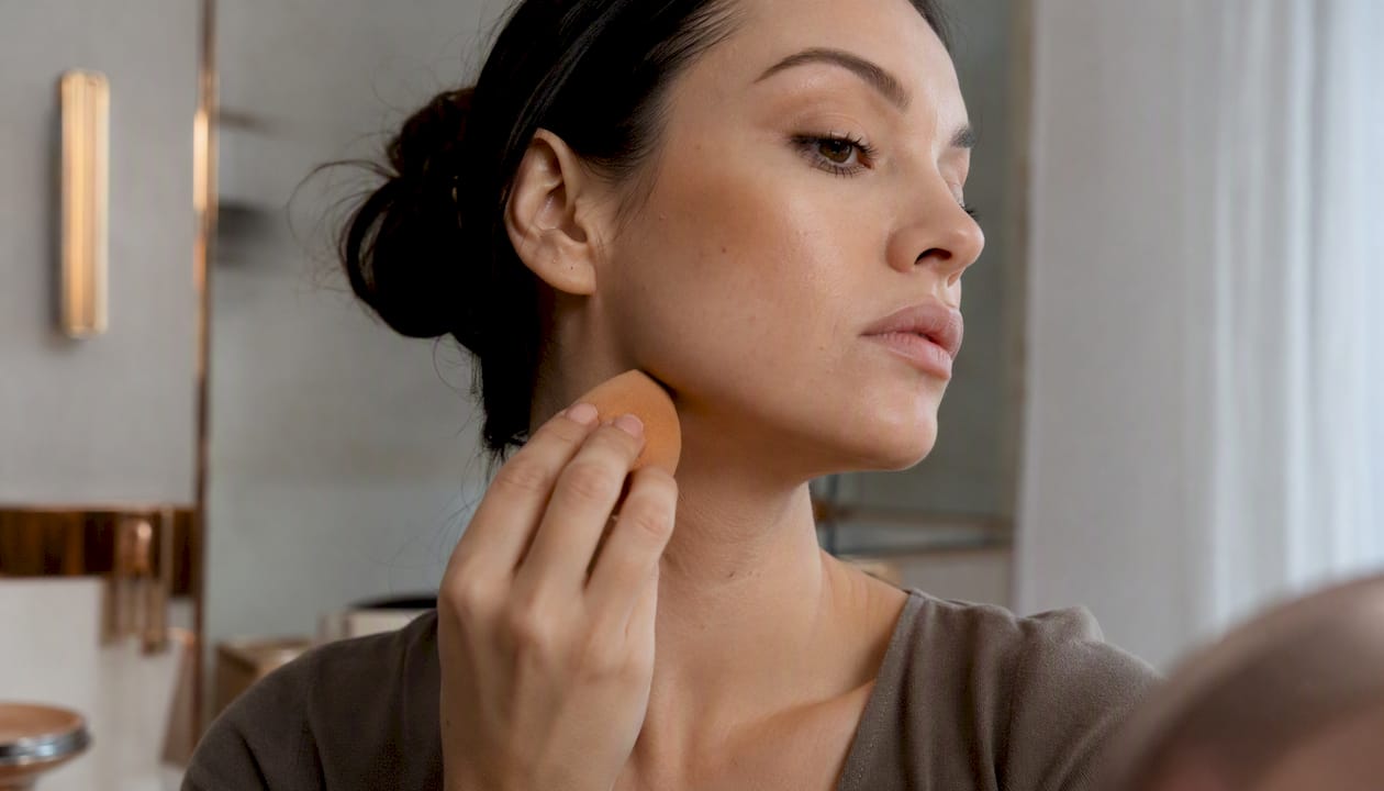 Hands blending cream bronzer with sponge