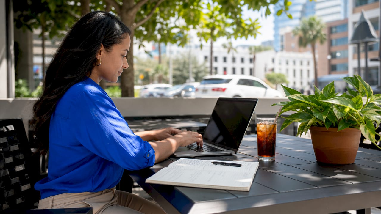 Hands typing on laptop with marketing notes nearby
