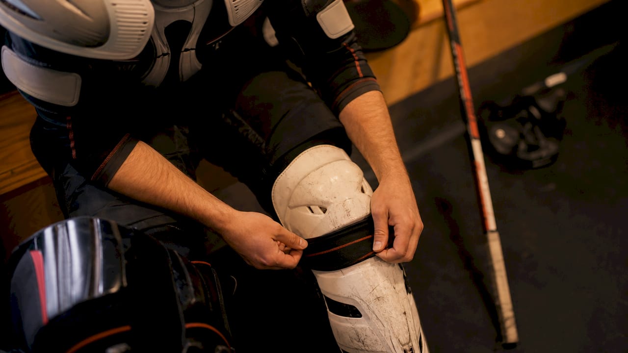 Close-up of hands adjusting hockey protective gear