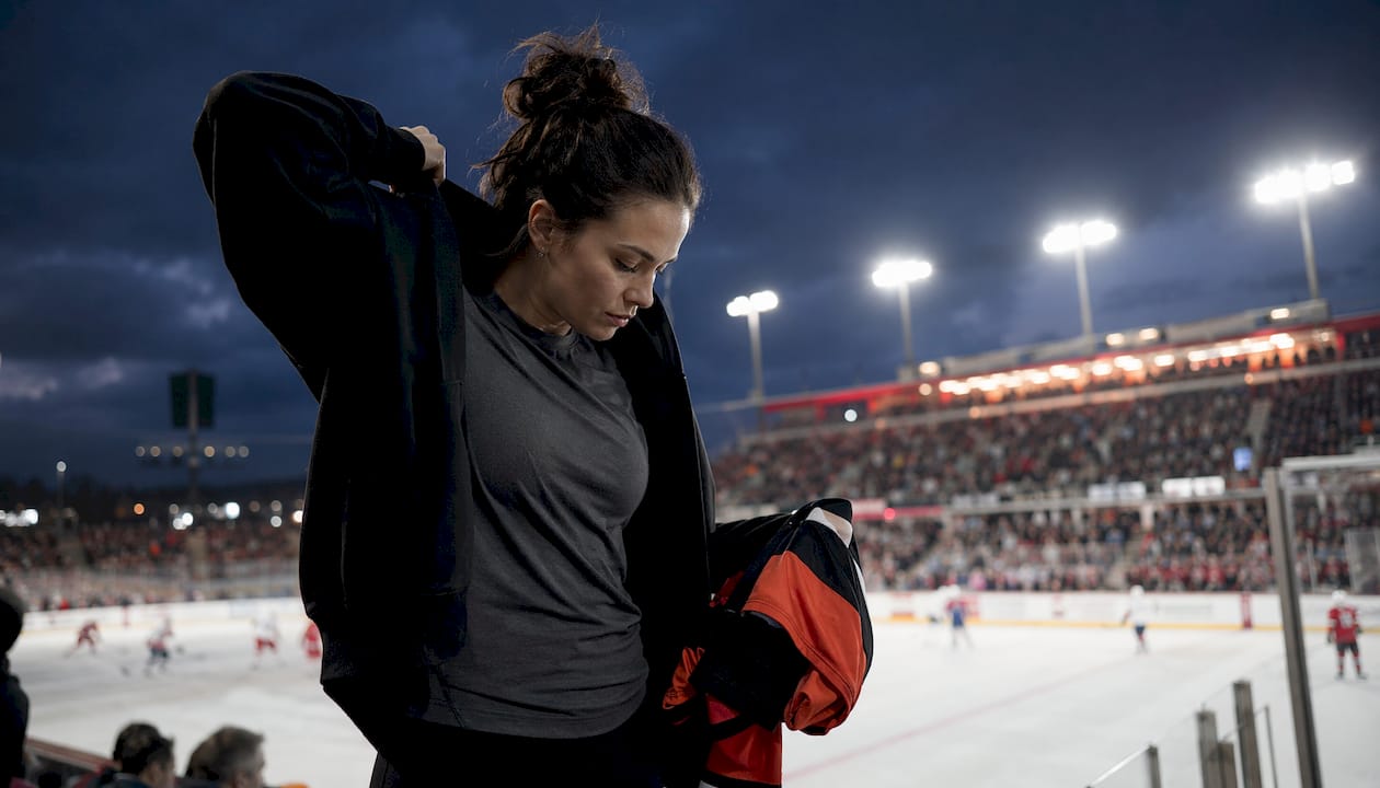 Fan layering hoodie indoors at hockey arena concourse