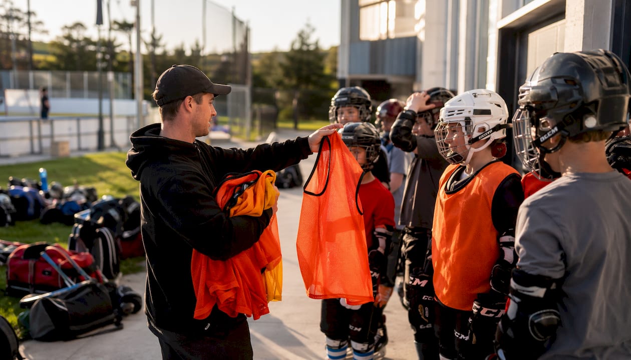 Coach handing mesh pinnies to youth players