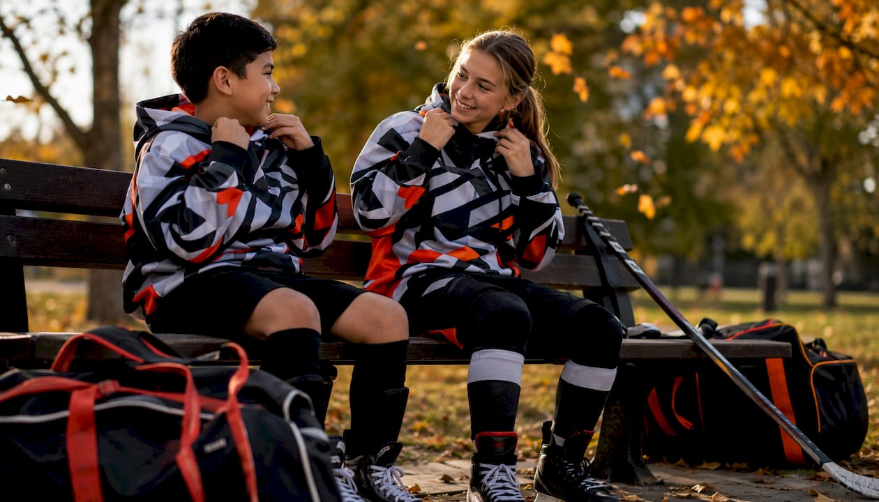 Youth hockey players wearing contrasting team hoodies outdoors