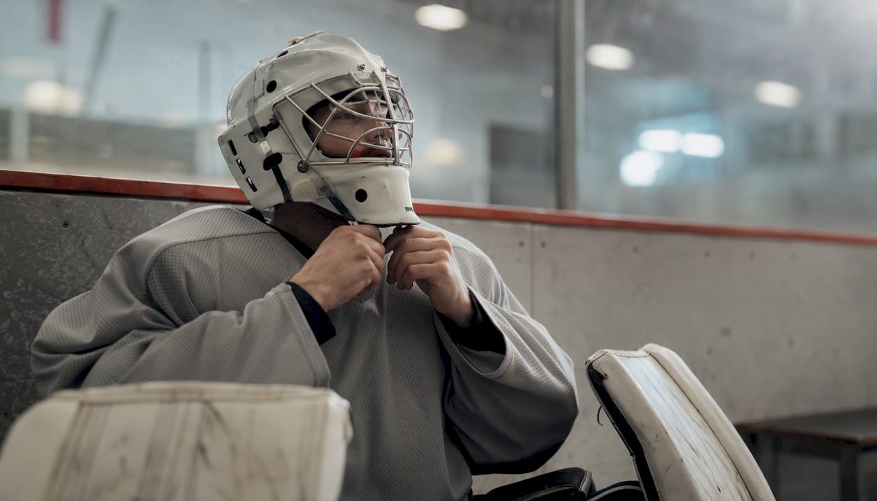 Goalie tightening side laces on padded jersey