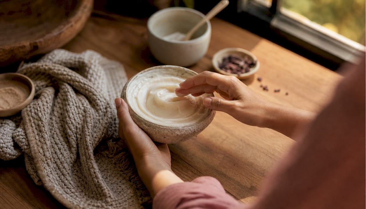 Close-up of hands holding cream jar on bathroom counter