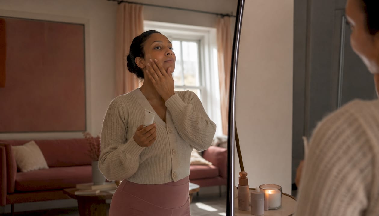 Woman applying tinted sunscreen to face indoors
