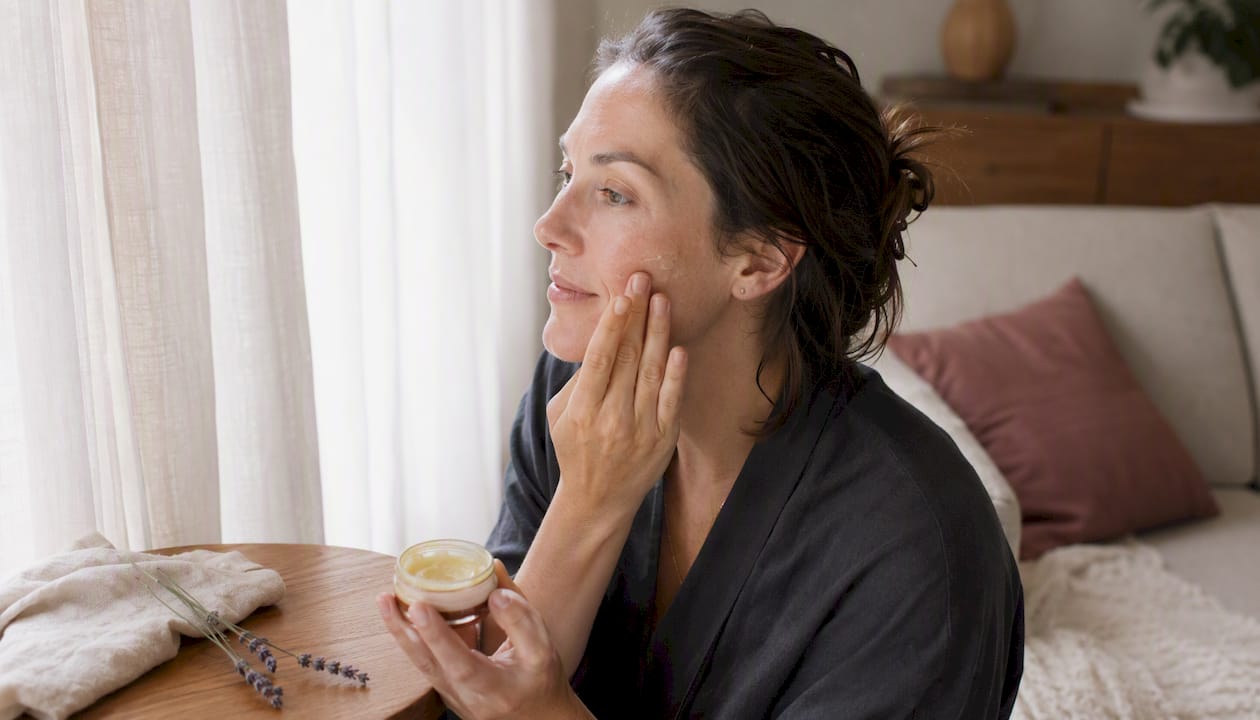 Woman applying soothing facial ointment at home