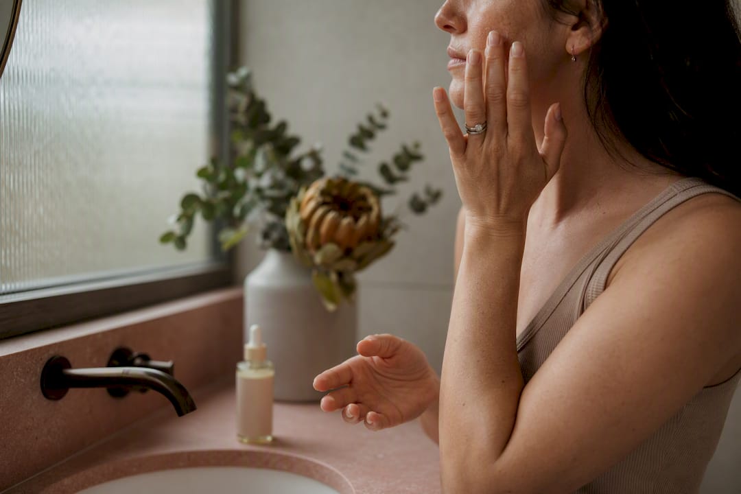 Woman applying serum to pigmented skin