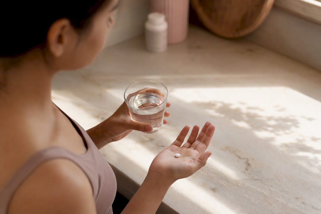 Woman holding pill and glass of water