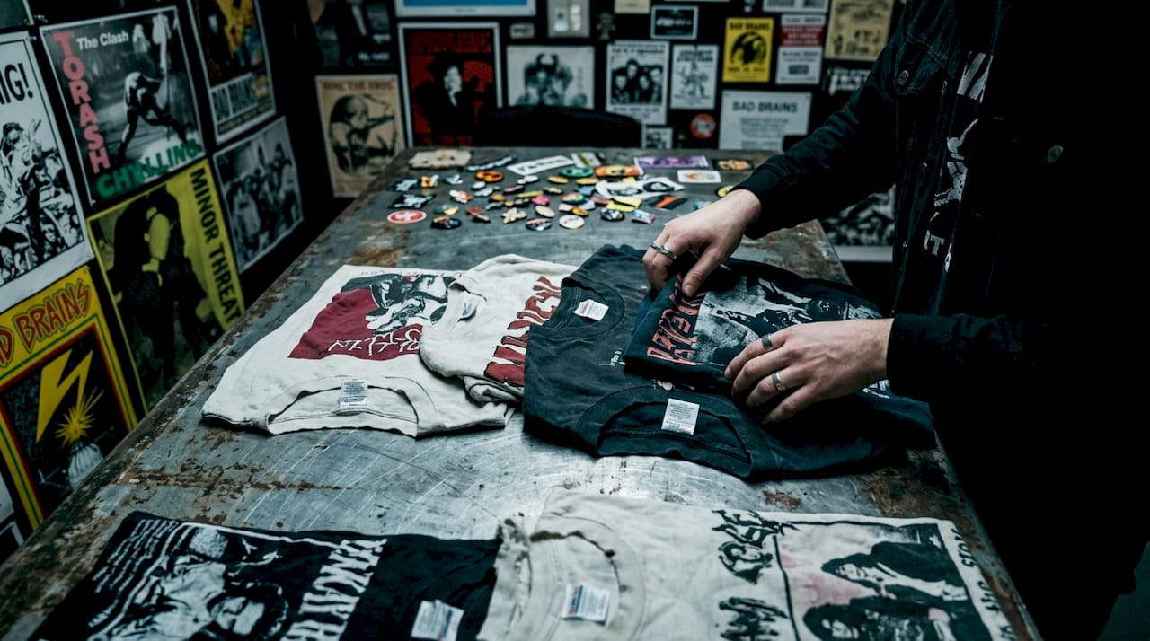 Hands sorting band t-shirts on wooden table