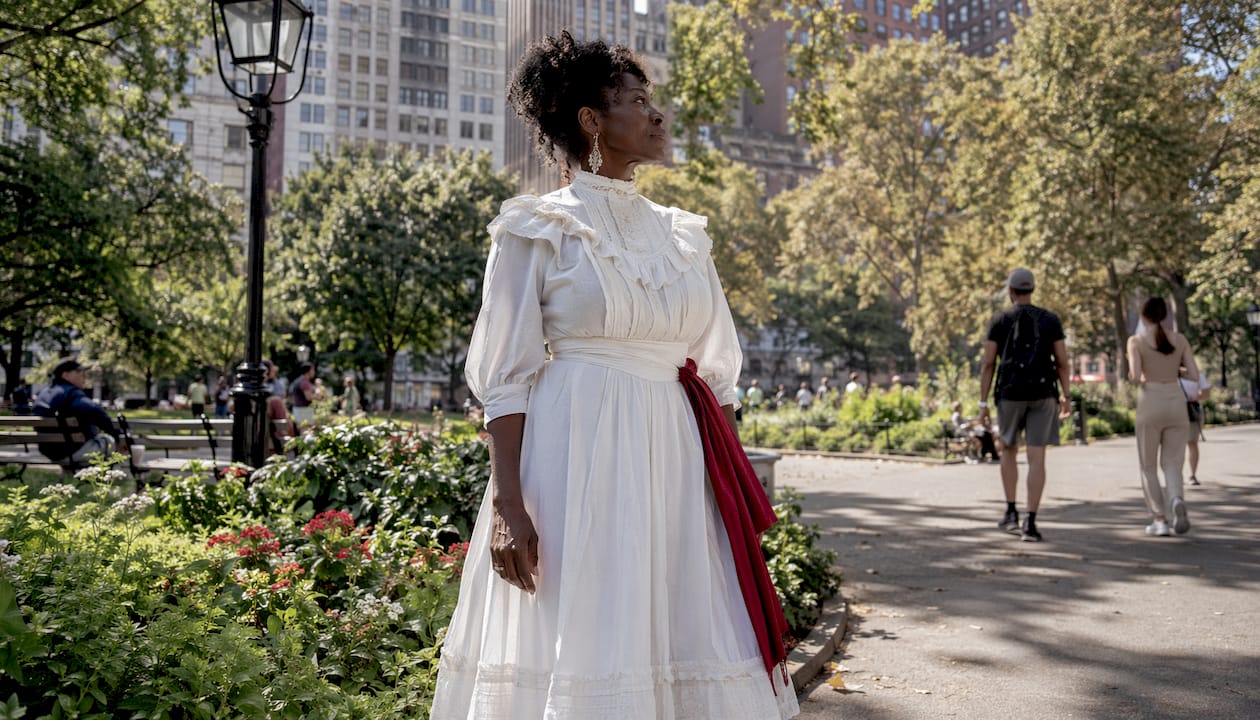 Woman in white suffragette dress in city