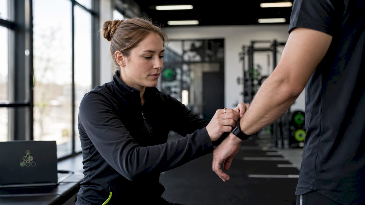 Scientist fitting heart rate monitor on athlete's arm