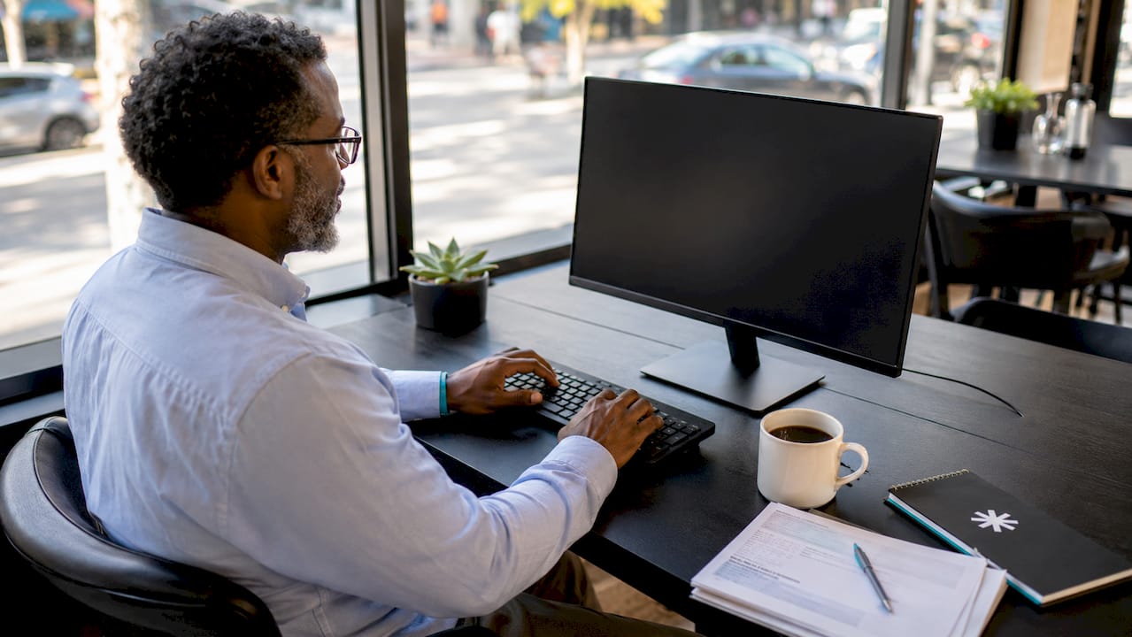Man at office desk with keyboard and blank monitor