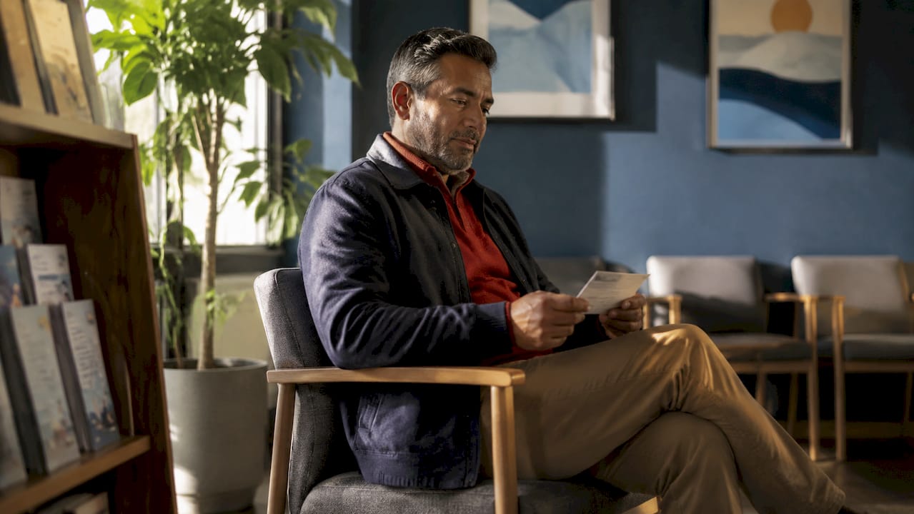 Man waiting in doctor's office holding appointment card