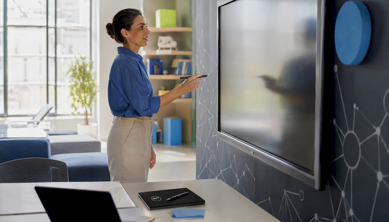 Hands with stylus poised on interactive touchscreen.