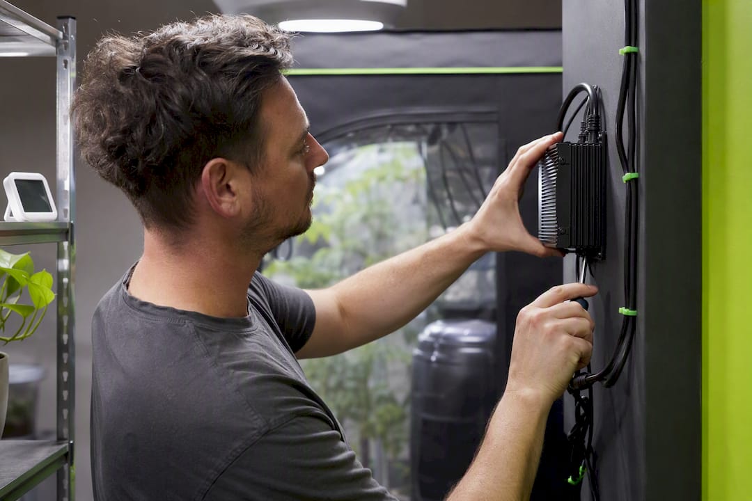 Hands mounting LED driver outside grow tent