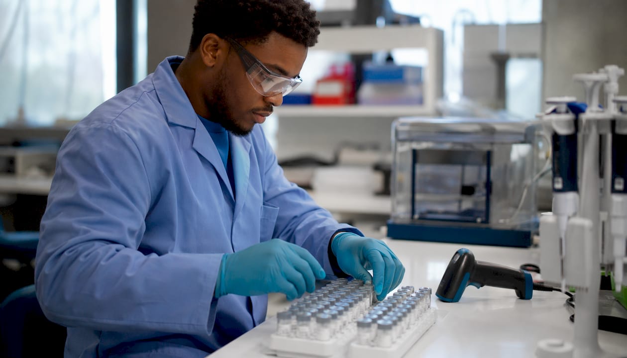 Technician scanning sample tube barcodes in lab