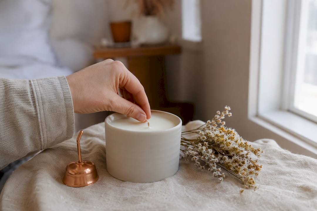 Hand trimming candle wick in bedroom