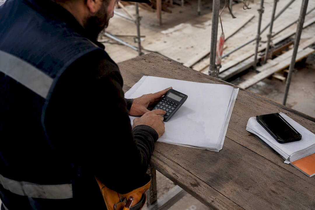 Gloved hands using calculator on site