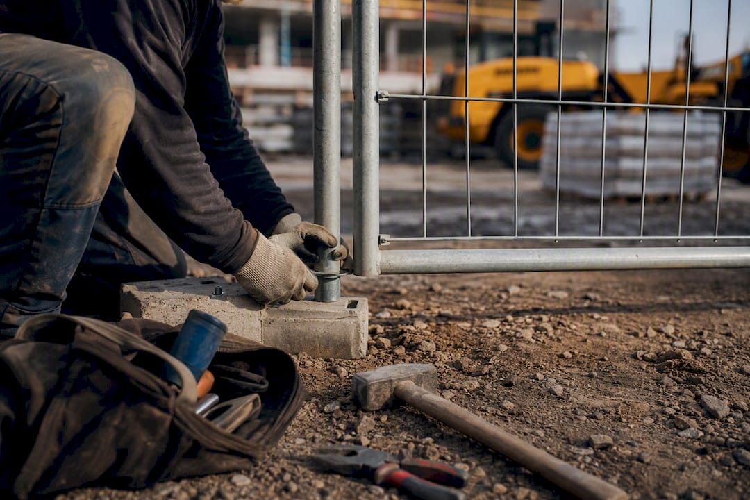 Hands assembling temporary fencing at construction site