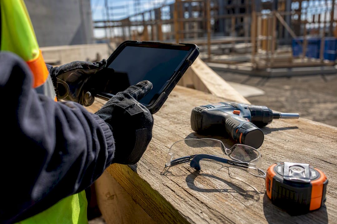 Hands holding tablet with construction tools nearby