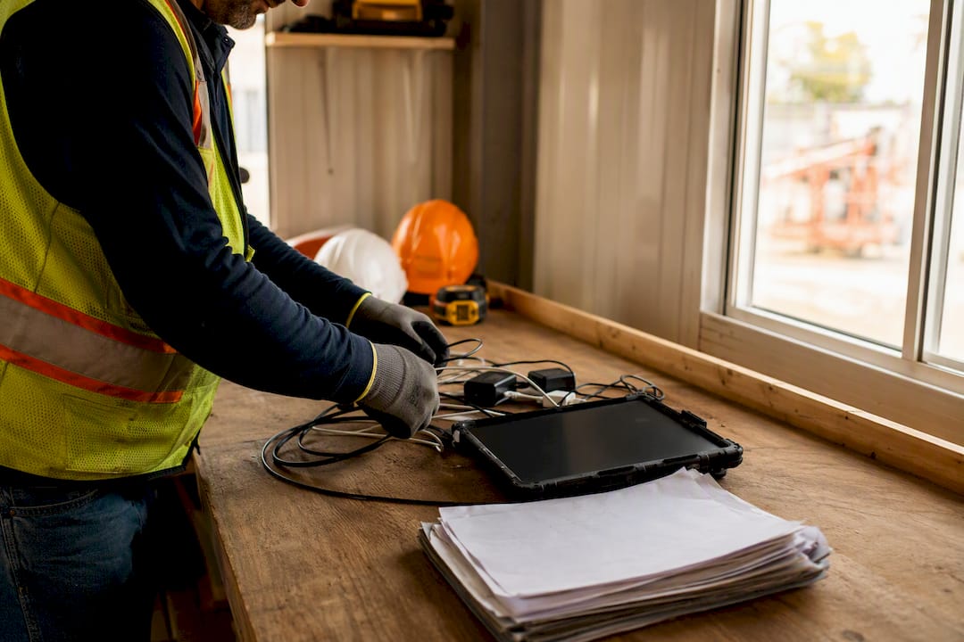 Hands managing tools and devices on construction site table